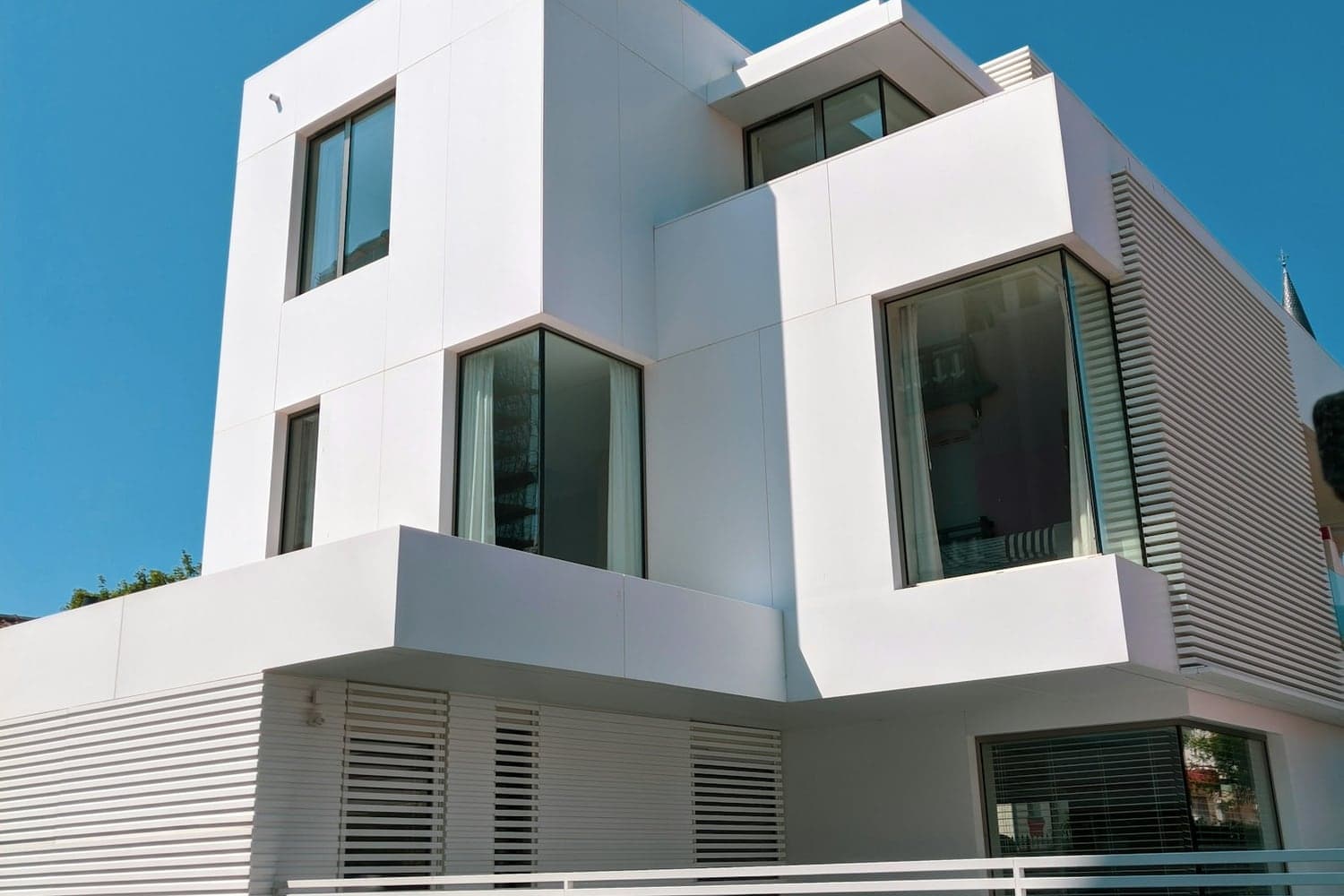 Fachada de casa residencial de dos niveles con ventanales y celosía